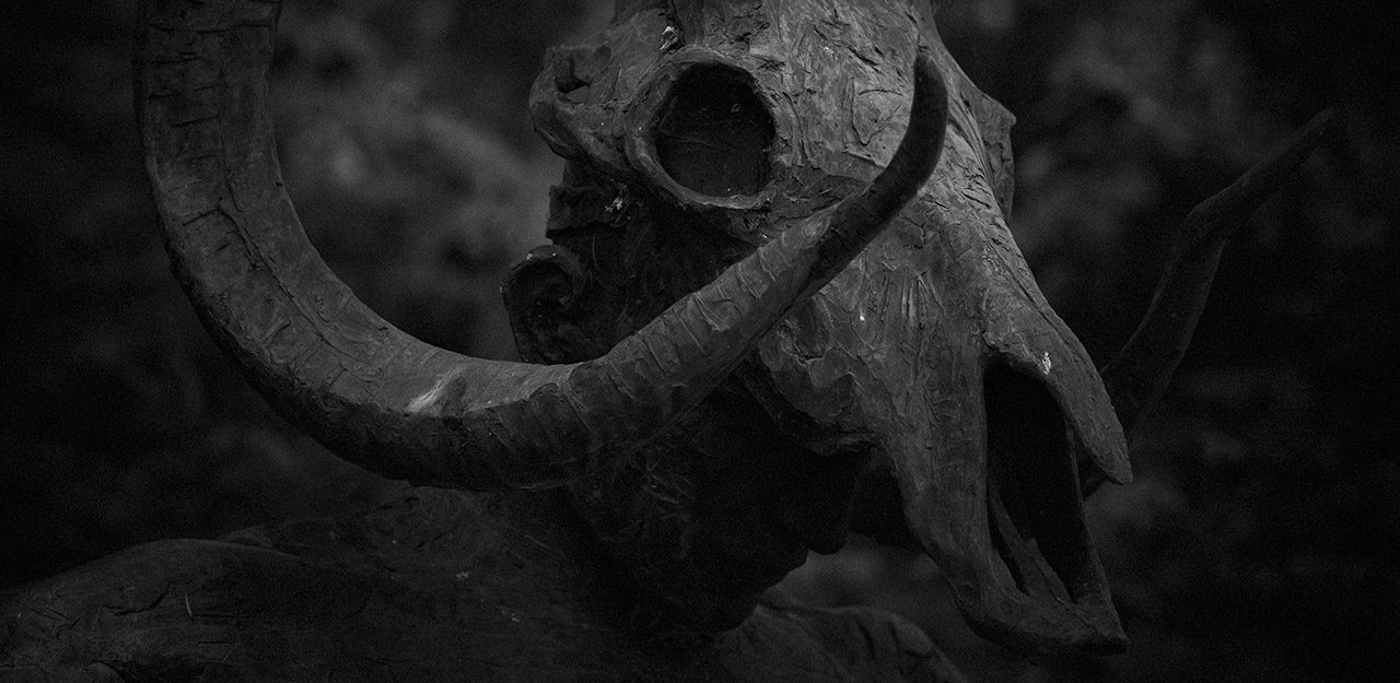 tatue à tête de créature cornue photographiée en noir et blanc dans le style de la photographie horreur à Fontainebleau