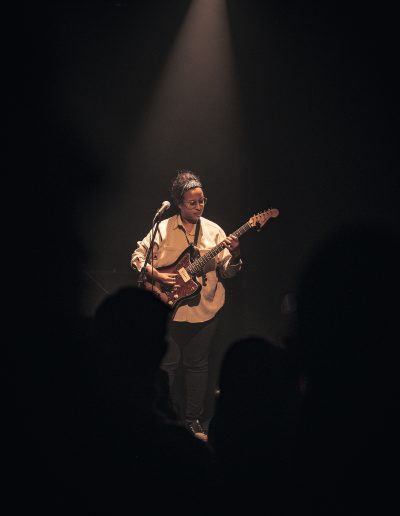 Photographie de concert - lumière de scène et chanteuse avec sa guitare